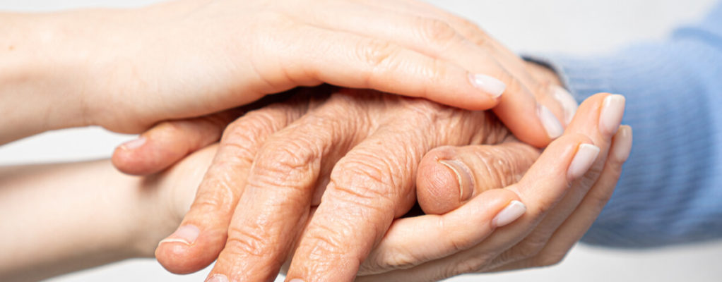 a younger person holds the hands of an older person
