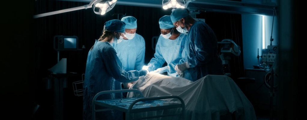 A group of surgeons work on a patient in an operating room