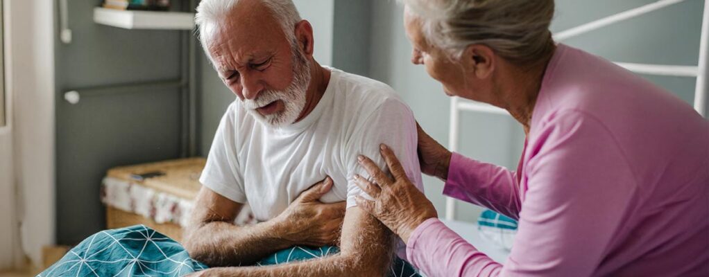 An older woman comforts an older man who appears to be in pain.