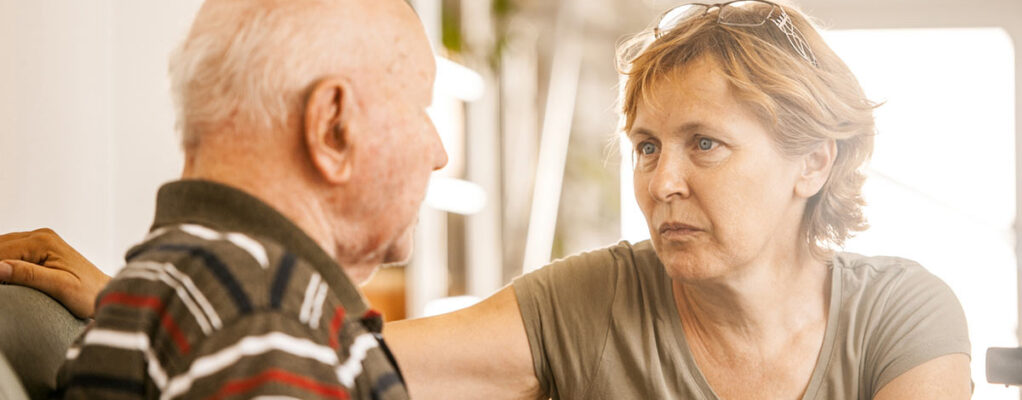 A woman who appears to be around 40-50 is looking intensely at a much older man who may be her father.